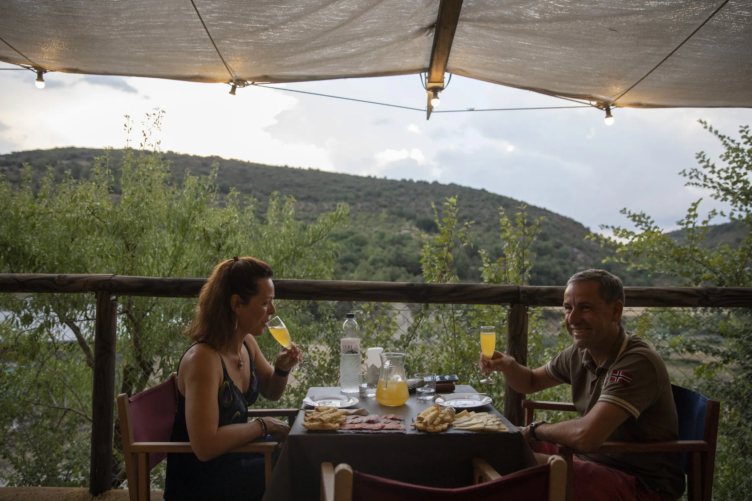 Una pareja brinda en su mesa con el valle al fondo